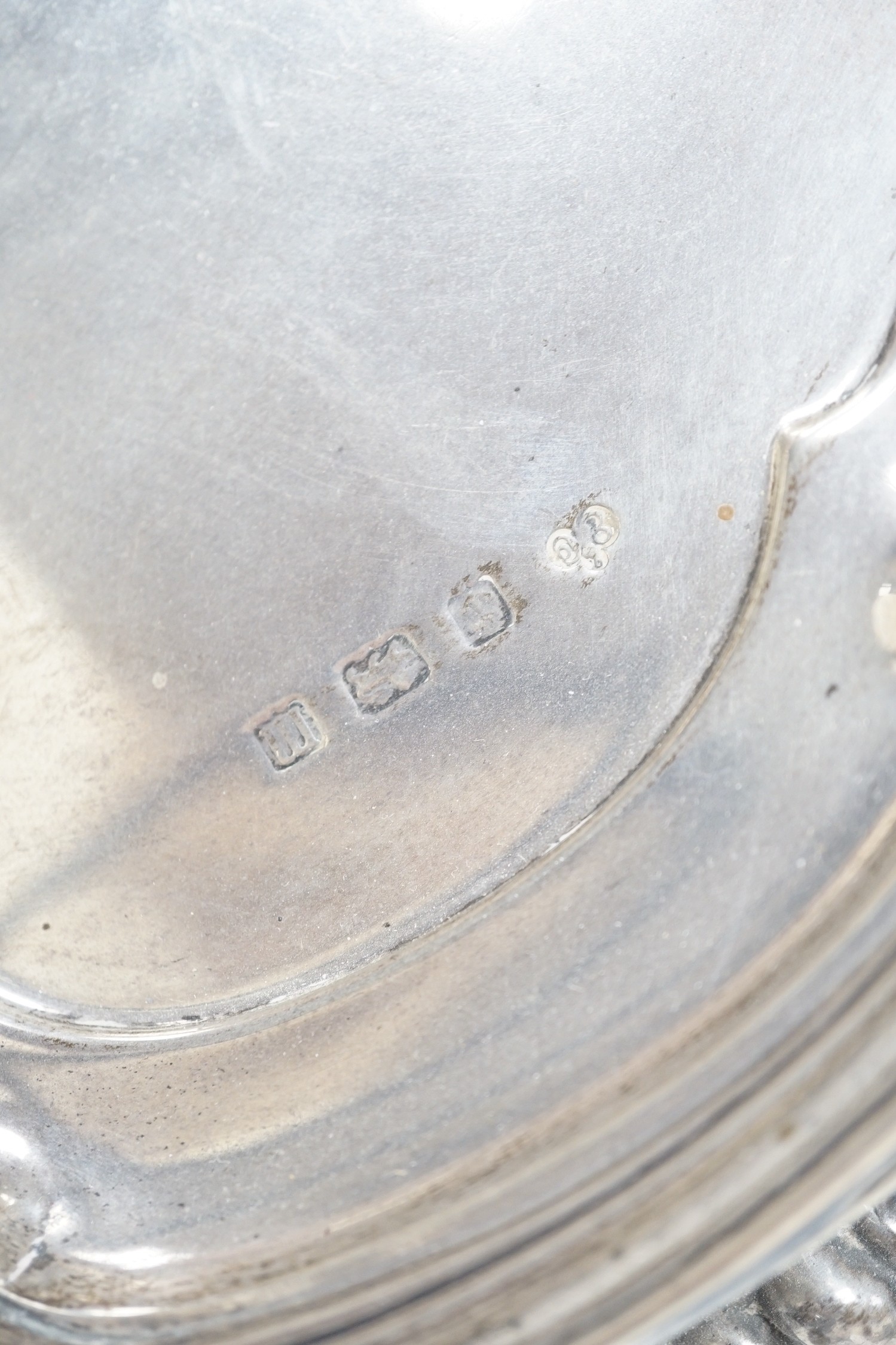 A George V silver salver by Elkington & Co, Birmingham, 1911, of shaped circular form with scroll border, on three scroll feet, diameter 37cm